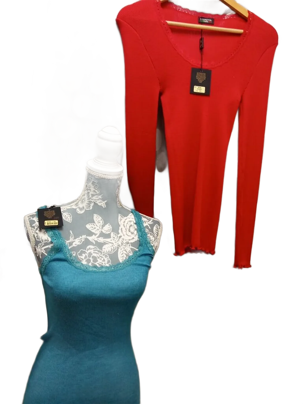 Un haut rouge à manches longues sur cintre en bois et un débardeur turquoise en dentelle sur un buste de mannequin à motif floral, devant un rideau gris à grands pois.