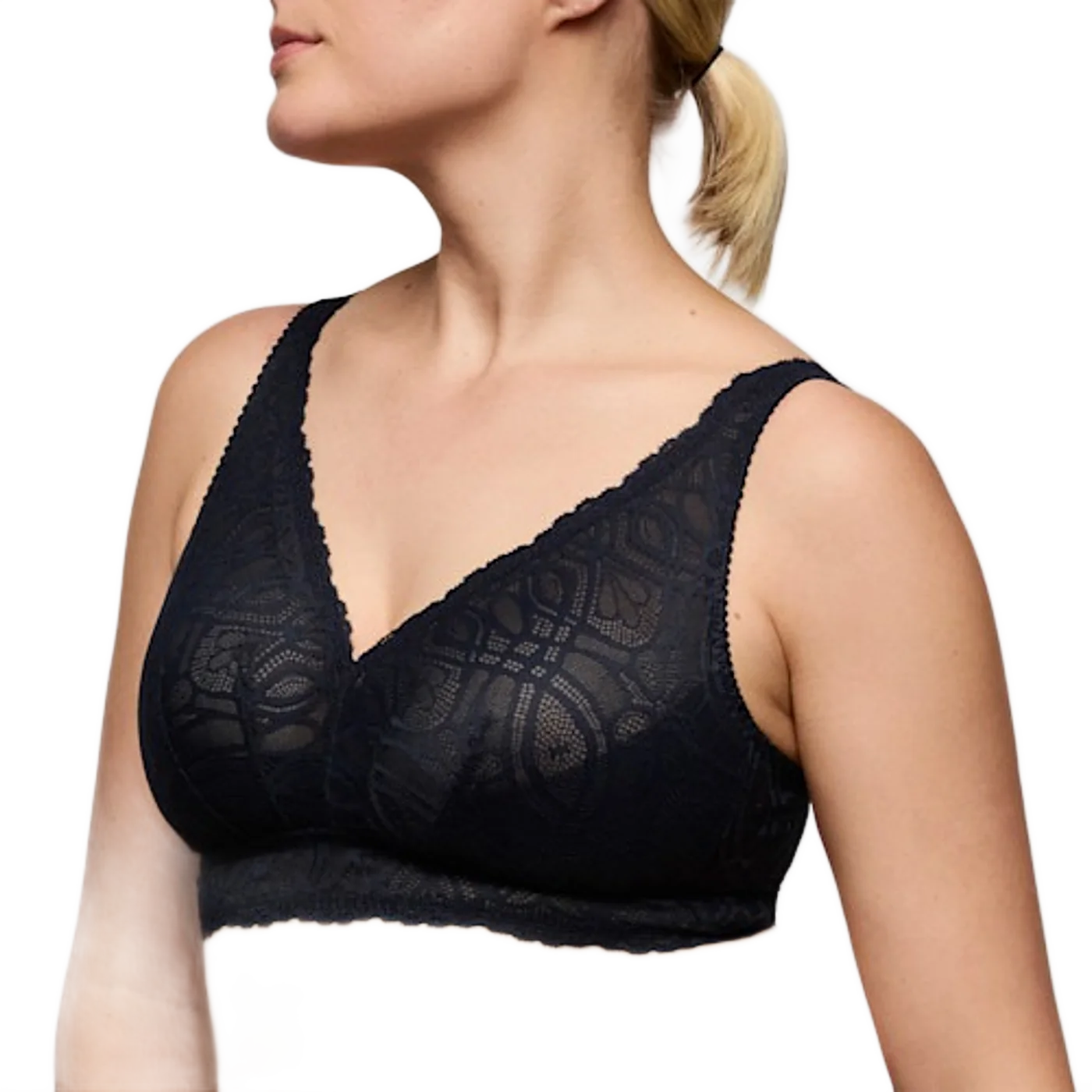 Une femme aux cheveux blonds attachés porte un soutien-gorge noir en dentelle ajourée, photographié de trois quarts sur fond gris clair.